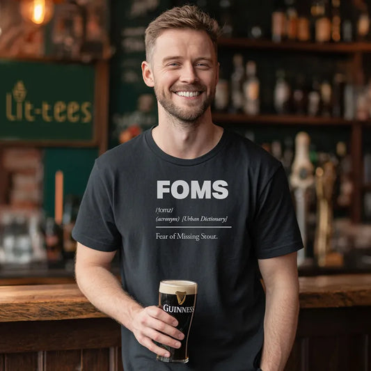 Black t-shirt with 'FOMS Fear of Missing Stout definition holding a Guinness glass in a bar setting.