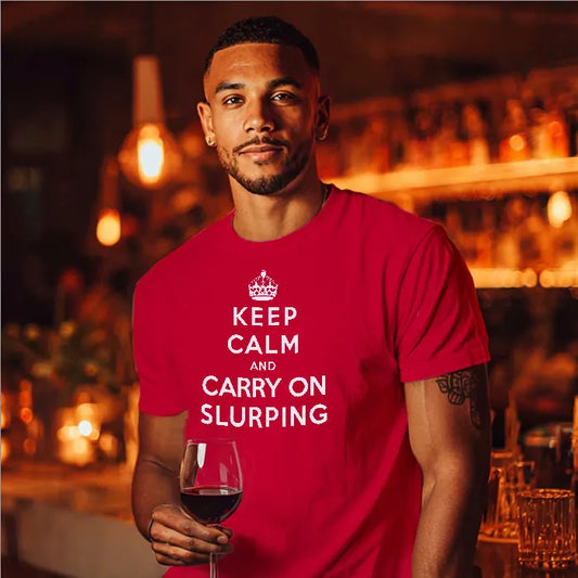 Man in bar holding a glass of wine and wearing a T Shirt saying Keep Calm and Carry on Slurping