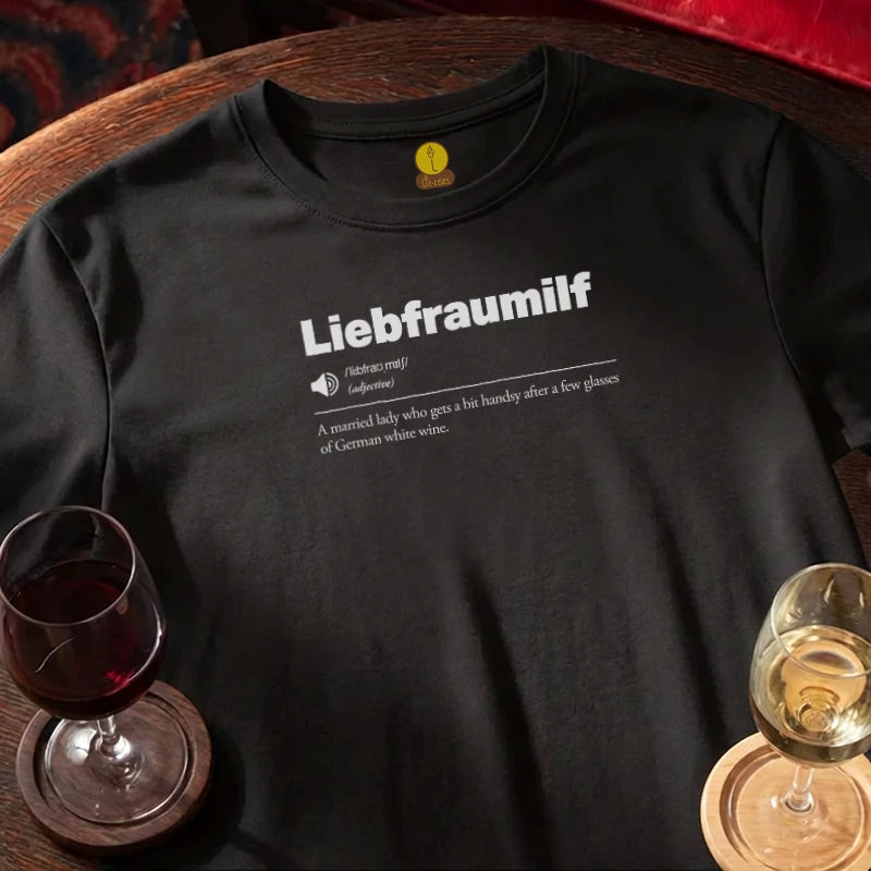 Black t-shirt with 'Liebfraumilf' definition print on a wooden bar surface with wine glasses.