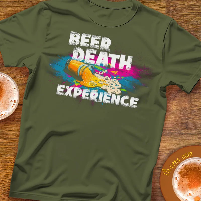 Green t-shirt with 'Beer Death Experience' graphic on a wooden surface with coffee cups.