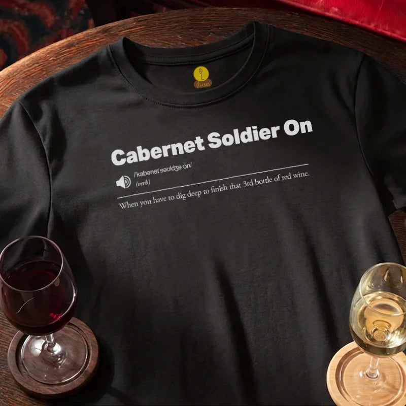 Black t-shirt with 'Cabernet Soldier On' text, wine glasses on a wooden bar table.