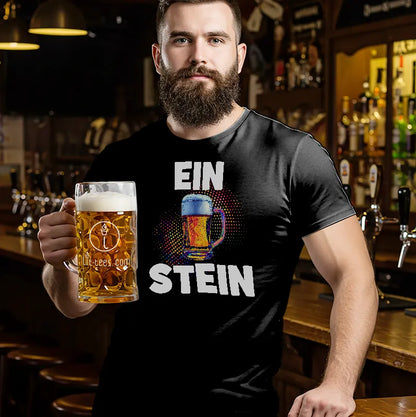 Man in a bar wearing a black t-shirt with humourous text saying 'EIN STEIN' holding a beer glass.