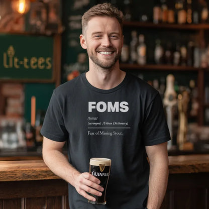 Black t-shirt with 'FOMS Fear of Missing Stout definition holding a Guinness glass in a bar setting.