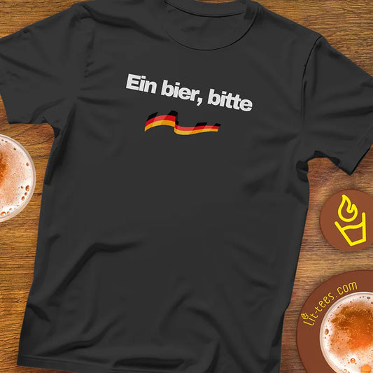 Black t-shirt with 'Ein bier, bitte' text and German flag on a wooden bar table