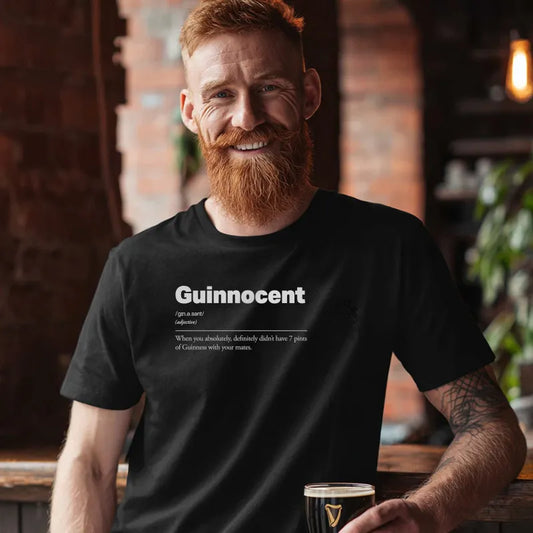 Man in a bar holding a beer wearing a black t-shirt with 'Guinnocent' definition text

