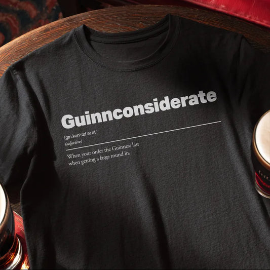 Black t-shirt with white text saying Guinnconsiderate on a wooden bar table