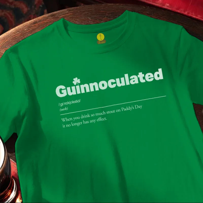 Green t-shirt with 'Guinnoculated' text on a wooden bar surface