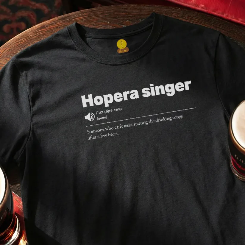 Black t-shirt with 'Hopera singer' text on a wooden bar table with beer glasses.