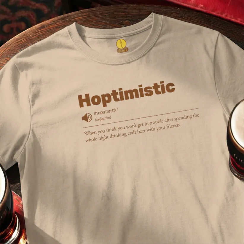 Beige t-shirt with 'Hoptimistic' text on a wooden bar table with glasses of beer.