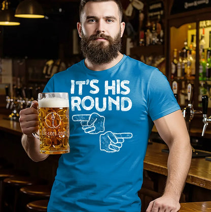 Man in a bar  holding a beer mug waering a blue beer themed t-shirt with 'It's His Round' text and graphic 