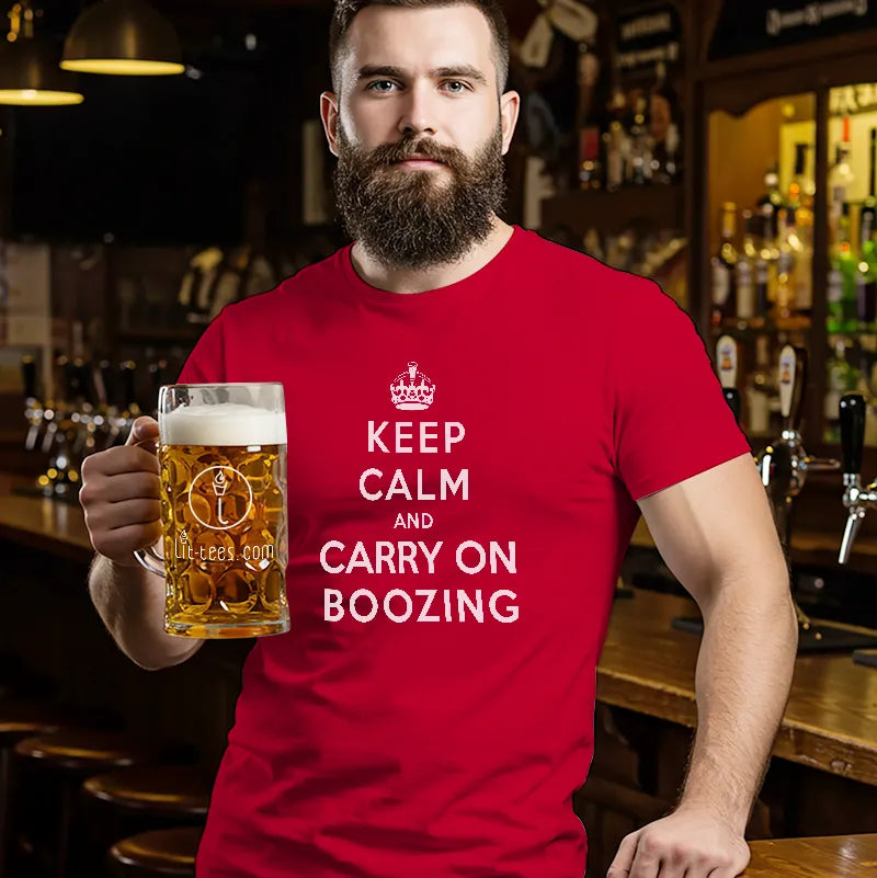 Man in bar holding a beer and wearing a red t shirt saying Keep Calm and Carry On Boozing