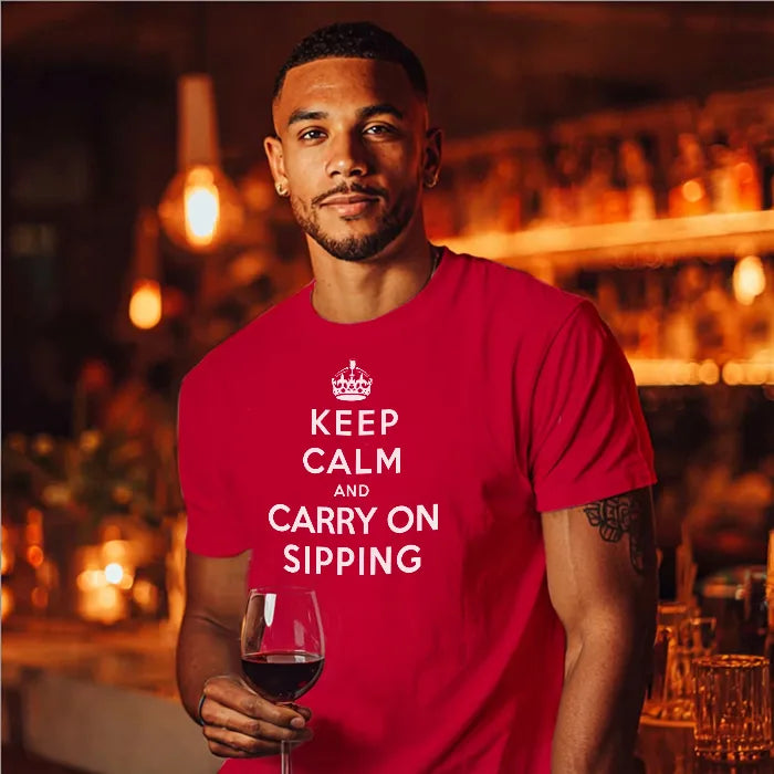 Man wearing a red t-shirt with 'Keep Calm and Carry On Slurping' text, holding a glass of wine in a bar setting.