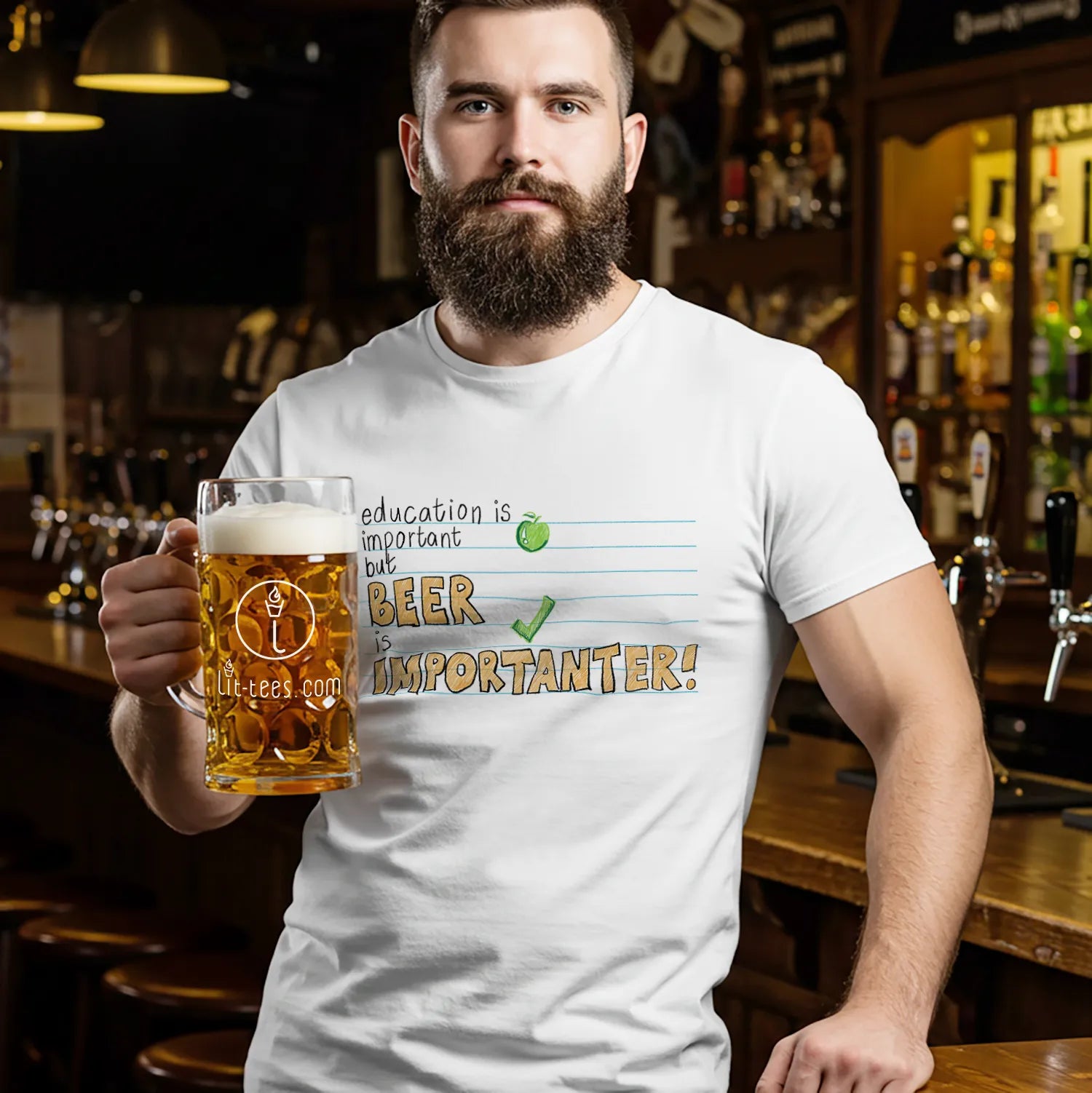 Man holding a beer mug in a bar wearing a white t-shirt with humorous text saying 'Education is important but beer is importanter' 
