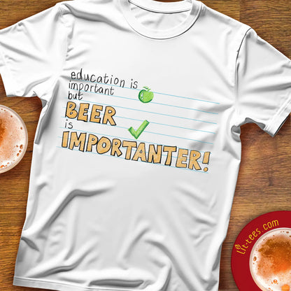 White t-shirt with humorous text saying 'Education is important but beer is importanter' on a wooden bar table