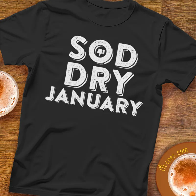Black t-shirt with 'SOD DRY JANUARY' text on a wooden surface with drinks.