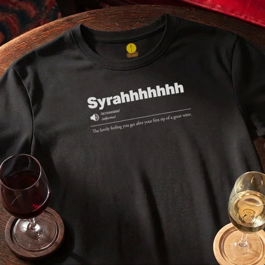 Black t-shirt with 'Syrahhhhhh' text on a wooden bar surface with wine glasses.